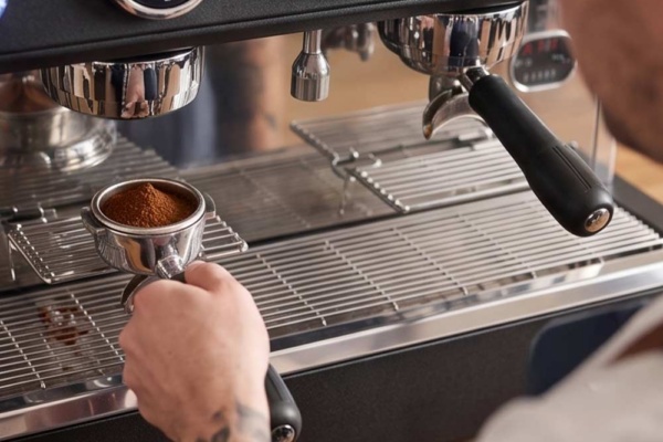 la Spaziale S21 2 Group Takeaway - hand placing coffee grounds into machine