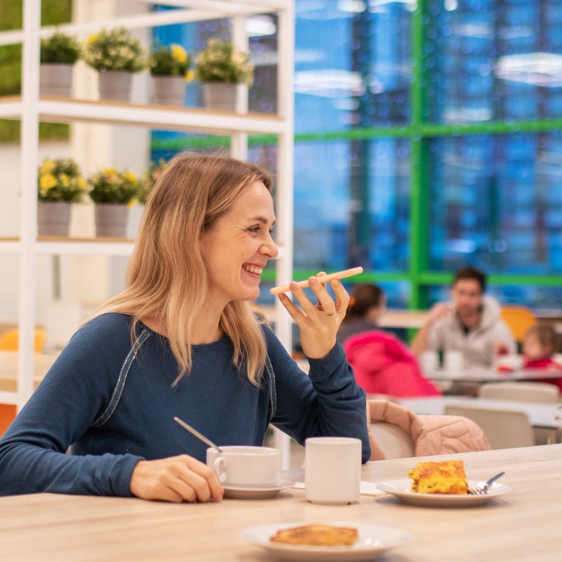 Woman talking on phone in cafe with coffee and cake