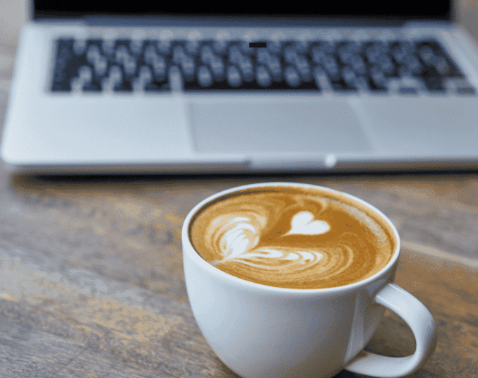Cup of coffee in front of open laptop
