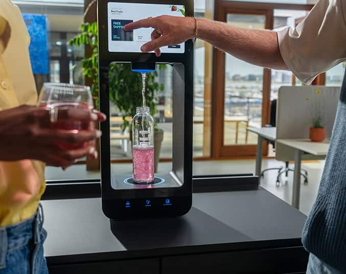People using an Aquablue machine to fill a bottle with flavoured water