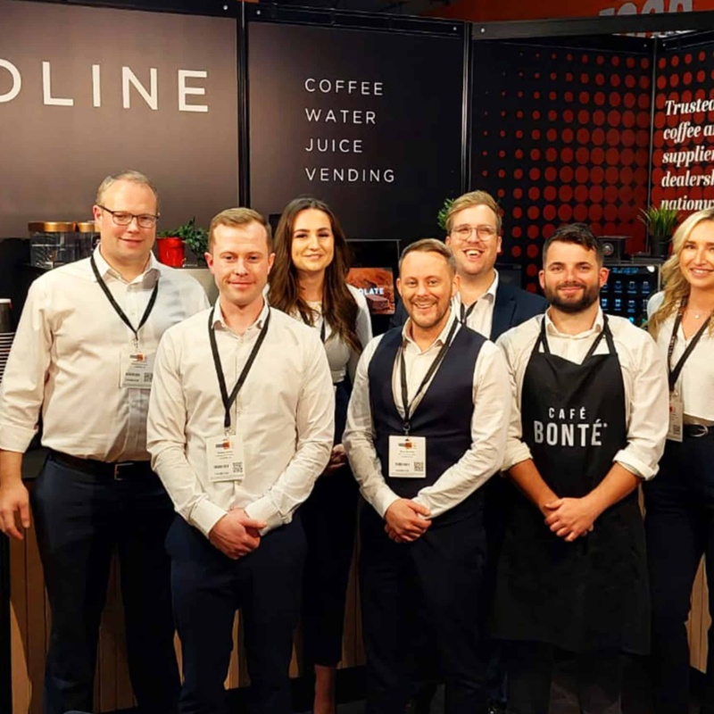 Liquidline exhibition stand with staff posing in front of demo machines
