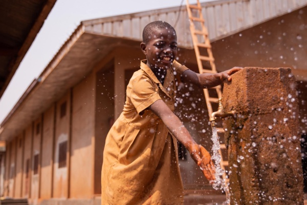 Child using water tap in Malawi village