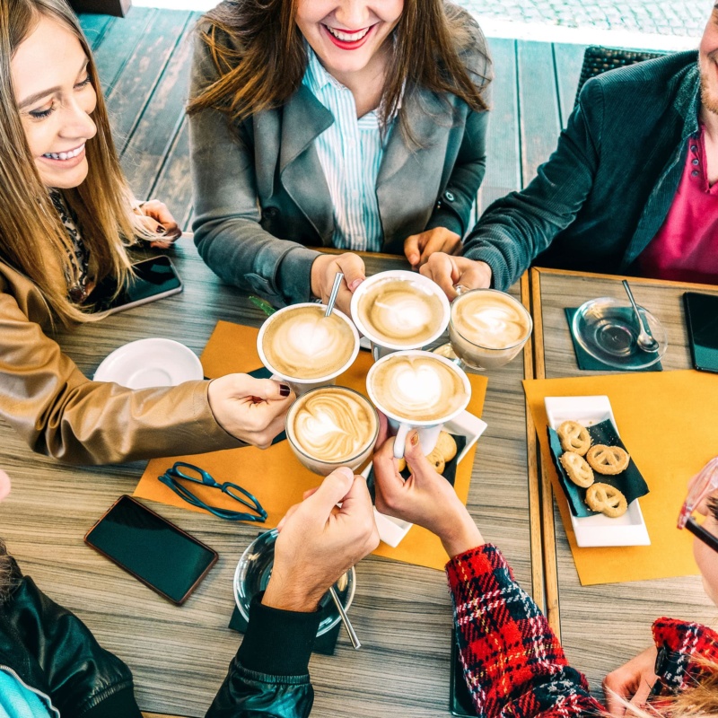 Friends toasting with cappuccino around a table