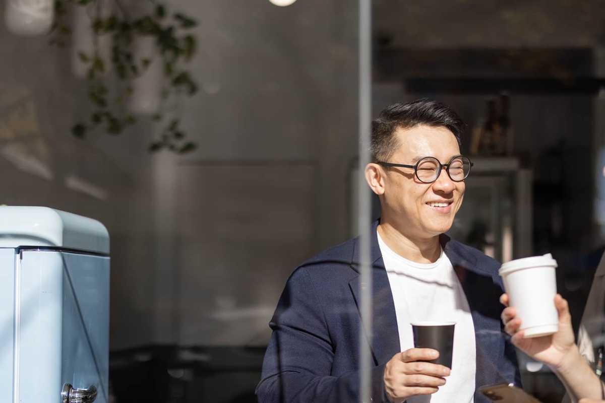 Two people enjoying coffee in kitchen area, looking from outside windows