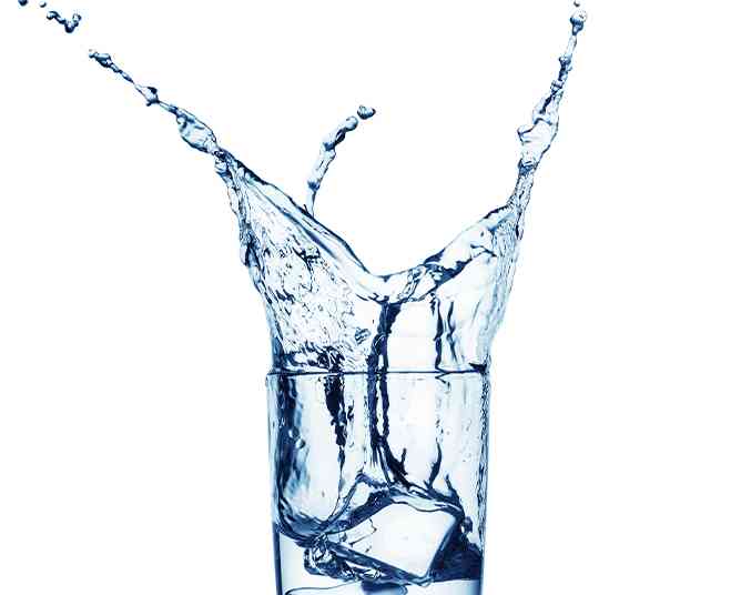 ice cube being dropped into a glass of water creating a splash