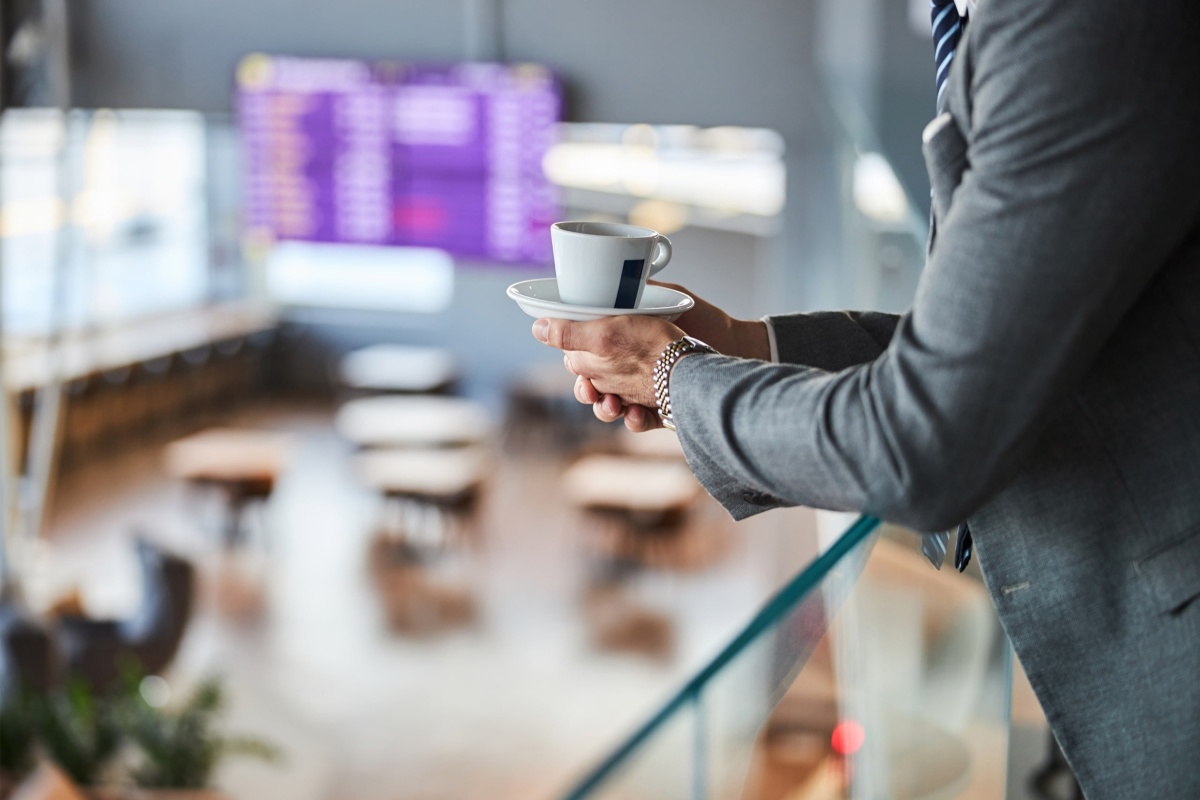 Man holding coffee cup in airport lounge