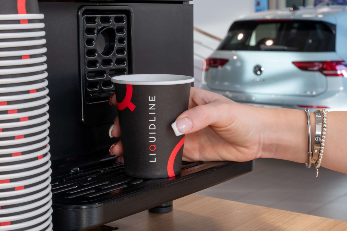 someone holding a liquidline cup waiting for coffee to dispense