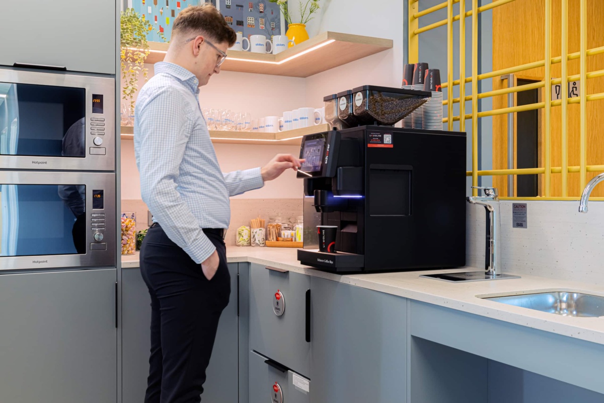member of staff using a bean to cup machine