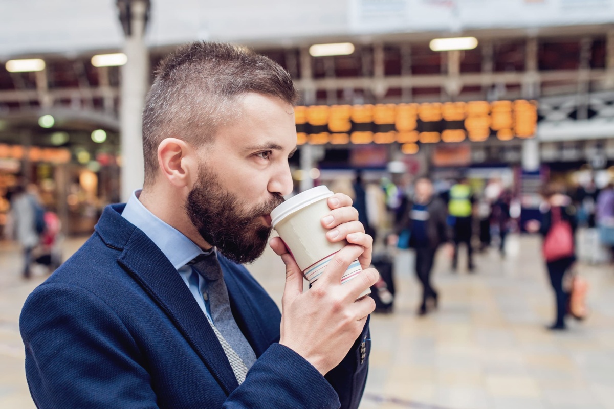 Man drinking coffee to go in train station