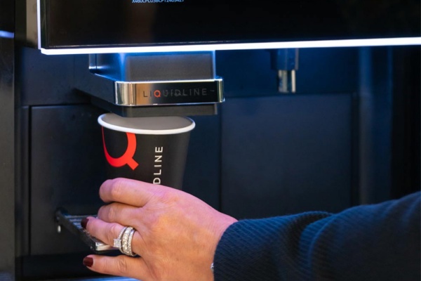 K2 fresh milk machine, hand placing cup under machine spout