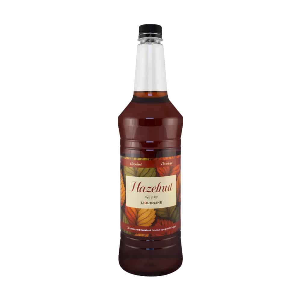 A bottle of Liquidline Hazelnut Syrup featuring an autumn leaf–themed label, filled with deep brown syrup, shown against a plain white background.