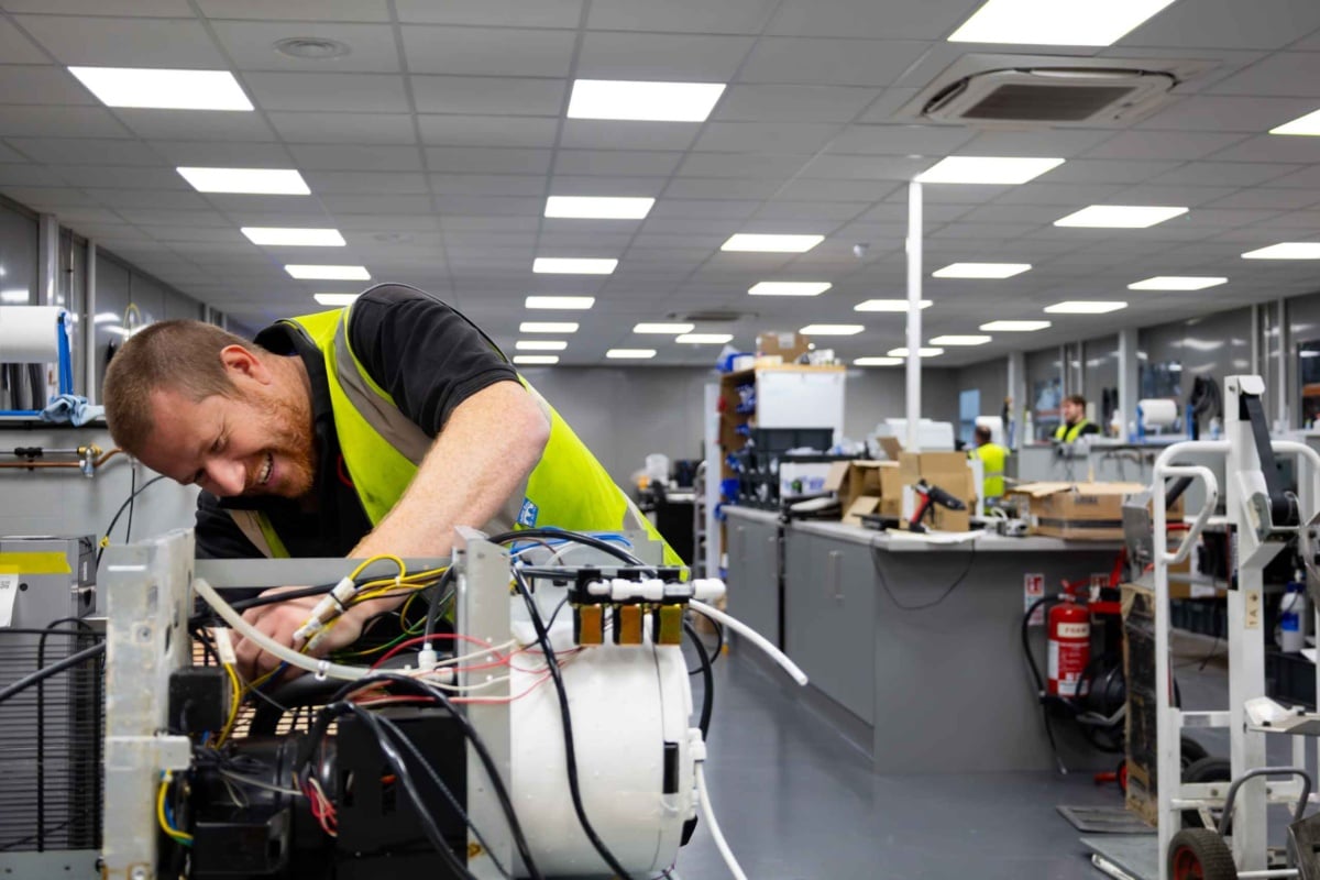 engineer repairing coffee machine, showing wires and the insides of the machine