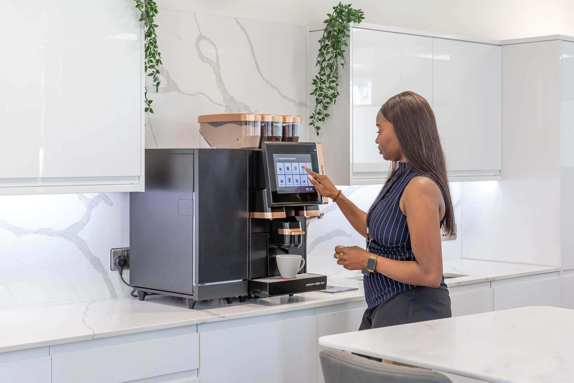 Woman dispensing coffee from a bean to cup machine