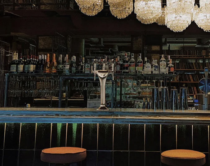 Chrome triple-faucet drinks tap dispensing water in a commercial refreshment area with beverage equipment in the background.