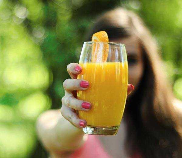 girl holding orange juice in glass