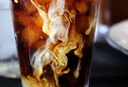 milk being poured into cold brew coffee