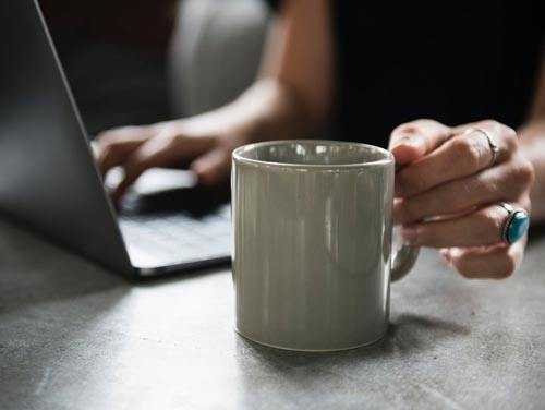 woman working next to mug of coffee