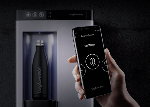 Hand holding smartphone that is displaying the Borg and Overstrom app. In the background a countertop water dispenser is filling a sports bottle