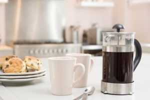 cafetiere on a table next to mugs and scones