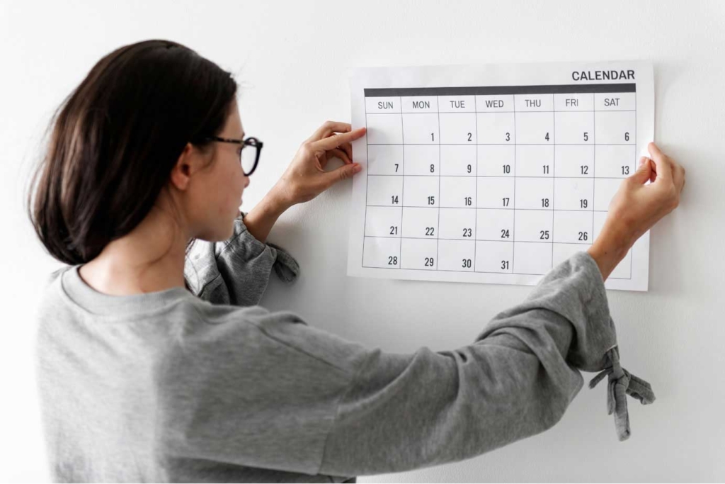 Woman sticking calendar to wall