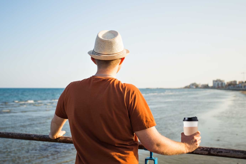Man by the sea holding a coffee