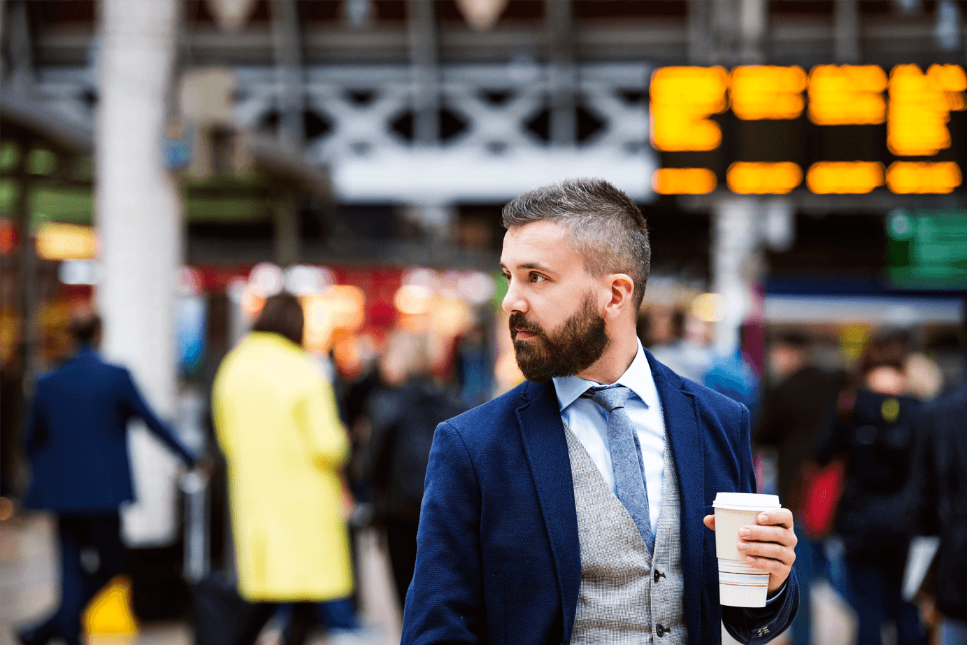 man holding coffee cup in busy station