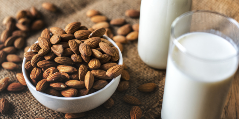 image of a pot of almonds with two glasses of almond milk beside it