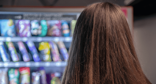 Back of someones head while they are looking at a Vivace vending machine