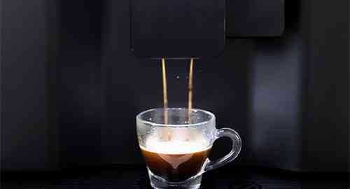 Coffee being dispensed by a Liquidline Q3 powdered milk bean to cup coffee machine into a glass espresso cup