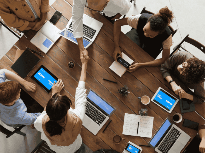 birdseye view of a meeting with laptops out and two people shaking hands across the table