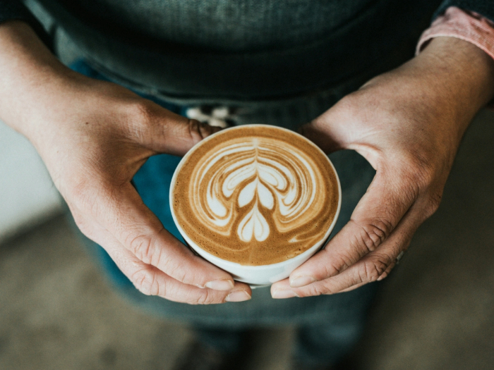 person holding a cup of coffee with coffee art
